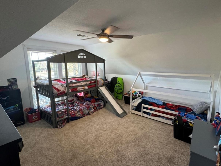 Carpeted bedroom featuring a ceiling fan, visible vents, a textured ceiling, and lofted ceiling