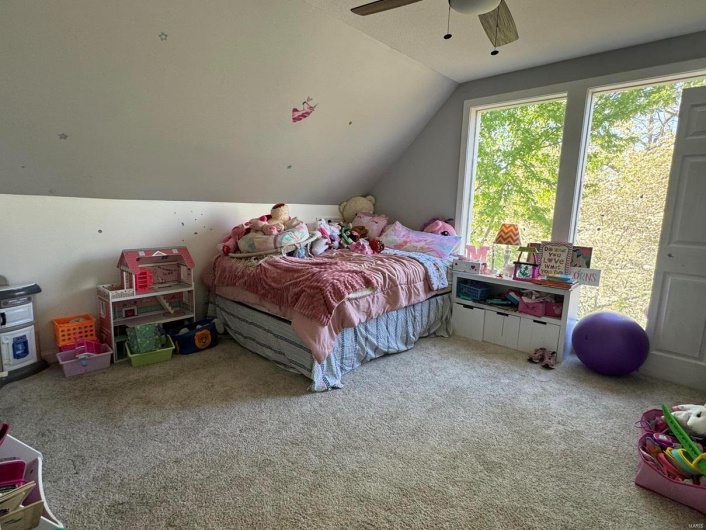 Carpeted bedroom with ceiling fan and lofted ceiling