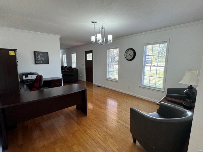 Office with plenty of natural light, a notable chandelier, ornamental molding, and wood finished floors