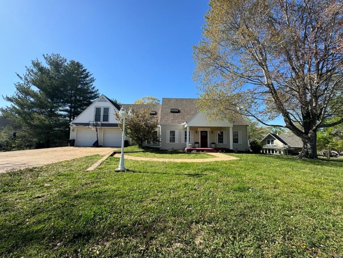 View of front of house with a front lawn, a shingled roof, and driveway