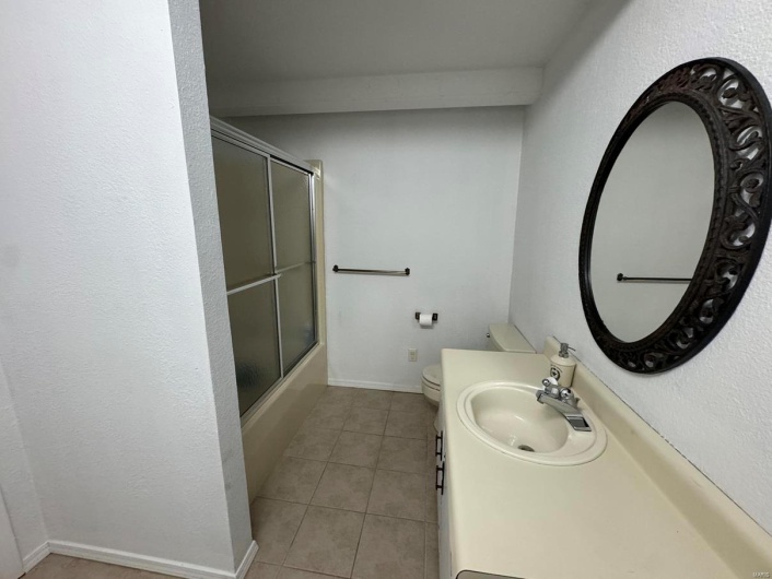 Bathroom featuring tile patterned floors, vanity, toilet, and bath / shower combo with glass door