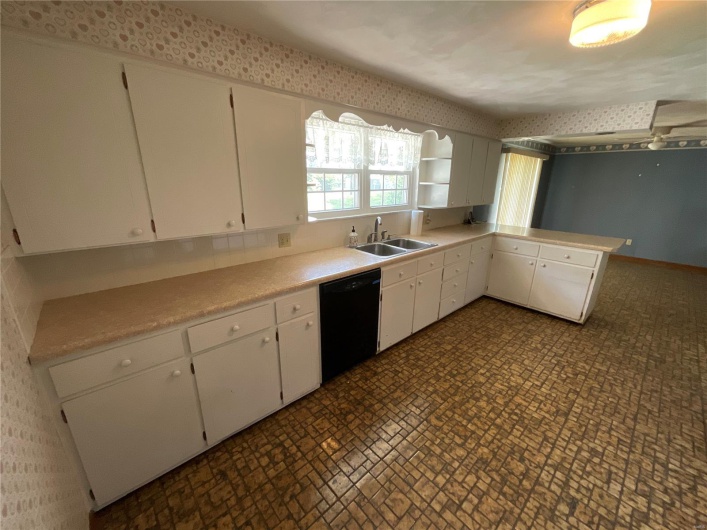 Kitchen with light countertops, dishwasher, white cabinetry, and a sink