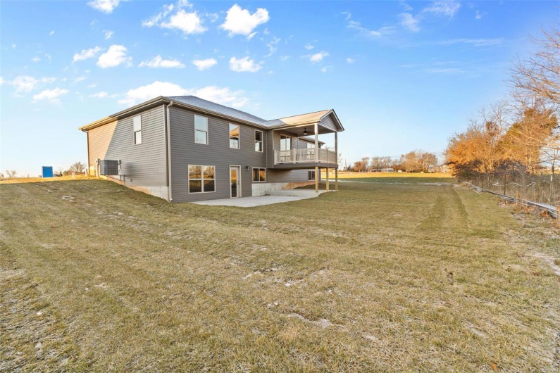 Rear view of property with central air condition unit, a patio area, a yard, and a balcony