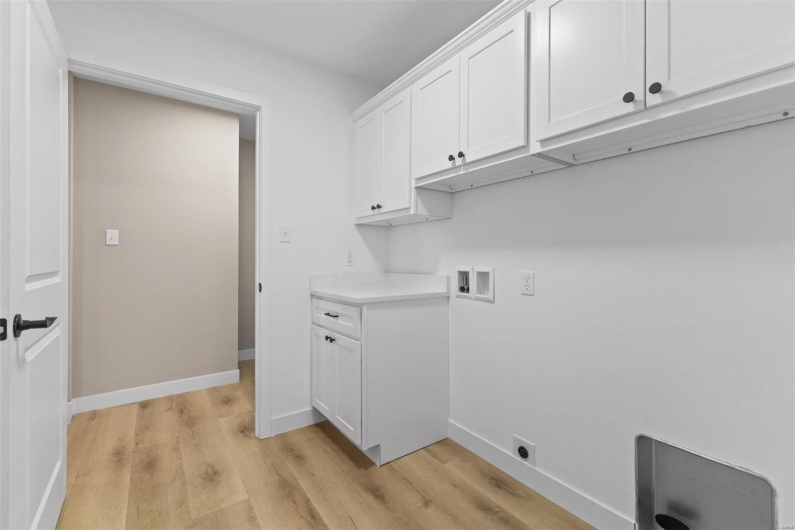 Laundry area featuring washer hookup, light hardwood / wood-style floors, and cabinets