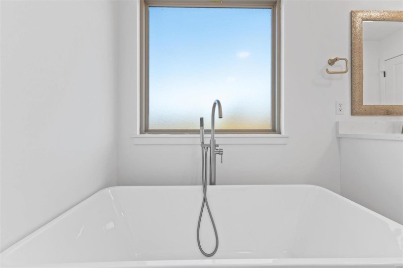 Bathroom featuring a bathing tub, a wealth of natural light, and sink