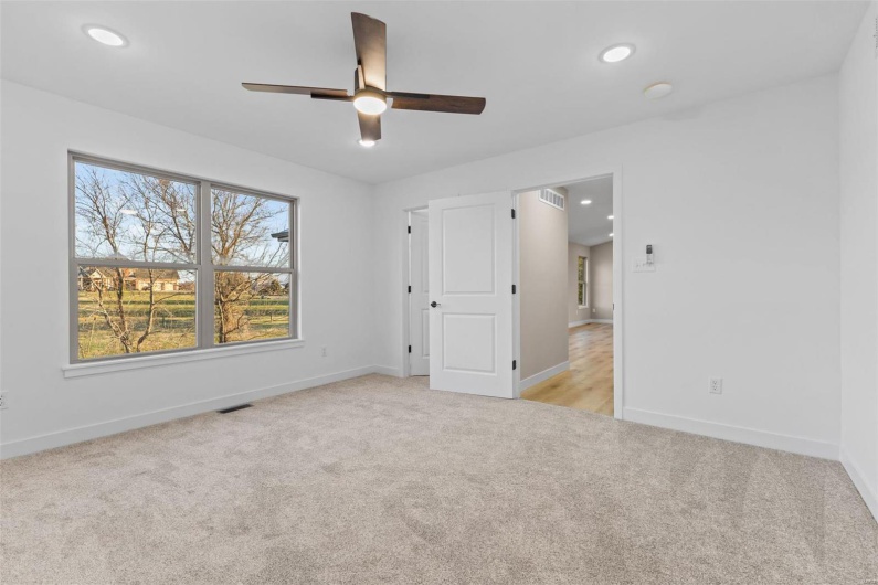 Unfurnished bedroom with light carpet and ceiling fan