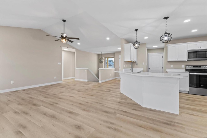 Kitchen featuring white cabinets, light wood-type flooring, stainless steel appliances, and vaulted ceiling