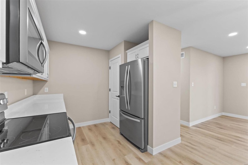 Kitchen with white cabinets, appliances with stainless steel finishes, and light wood-type flooring