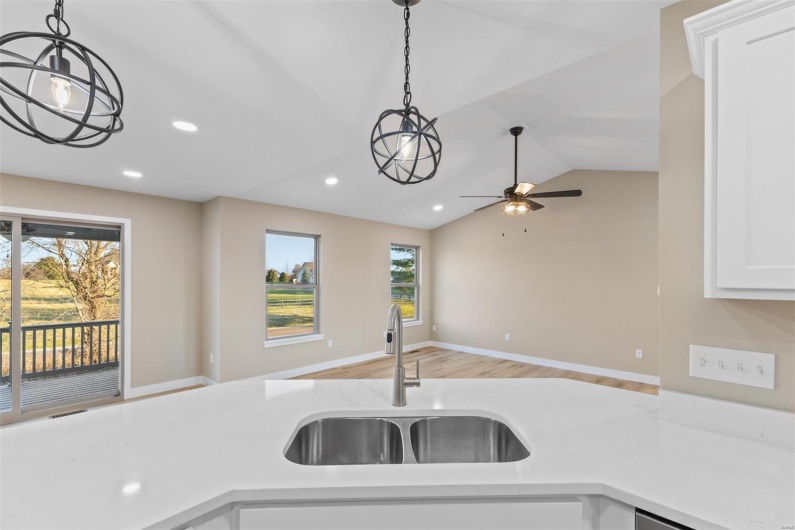 Kitchen with ceiling fan, a wealth of natural light, lofted ceiling, and sink
