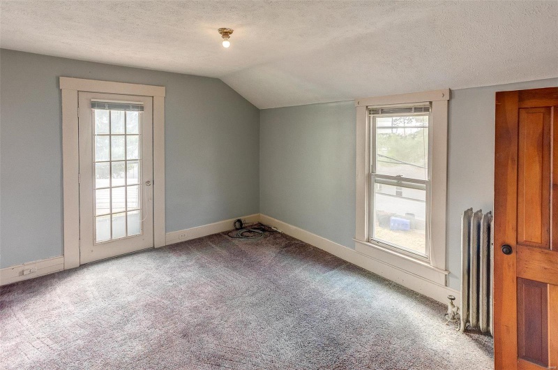 Additional living space featuring carpet floors, a textured ceiling, lofted ceiling, and plenty of natural light