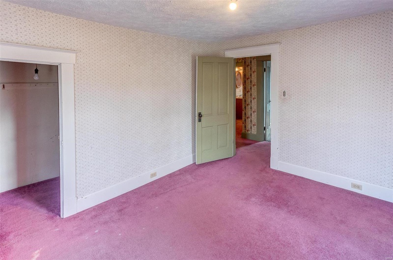 Unfurnished bedroom featuring a closet, a textured ceiling, baseboards, wallpapered walls, and carpet floors