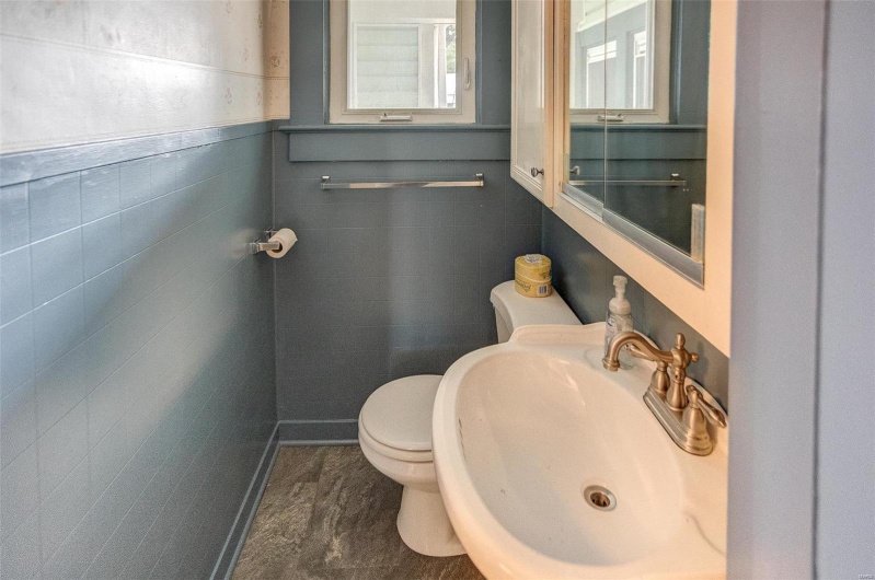 Bathroom with tile walls, toilet, and a sink