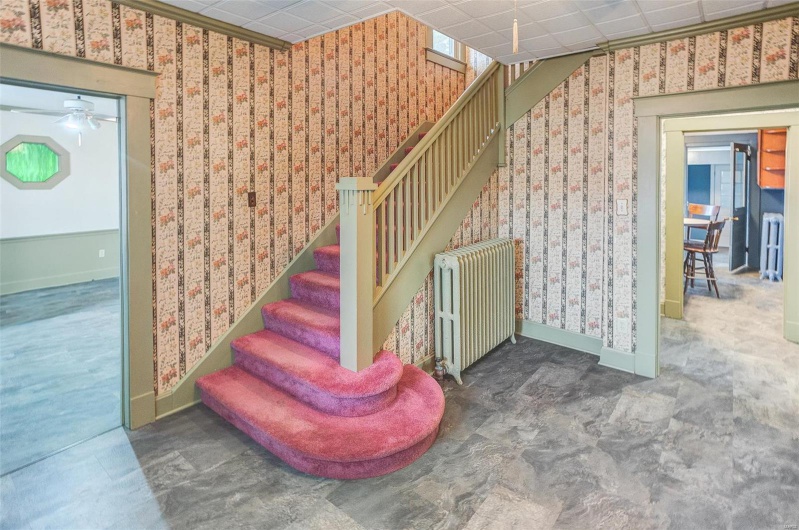 Stairway with baseboards, wallpapered walls, radiator heating unit, and a ceiling fan