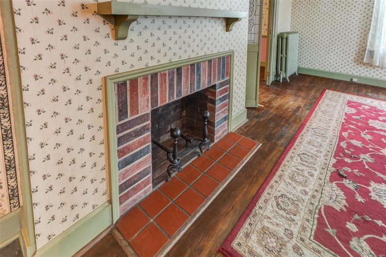 Living room featuring baseboards, wallpapered walls, radiator heating unit, a fireplace, and wood finished floors
