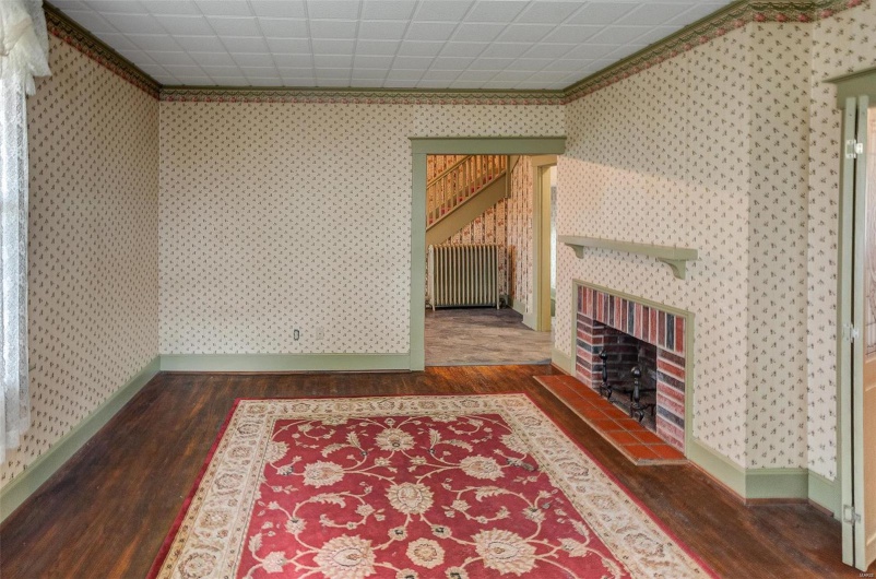 Living area featuring wallpapered walls, radiator heating unit, and wood finished floors
