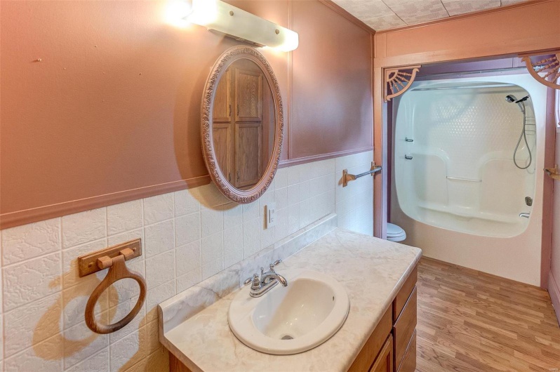 Full bathroom featuring a wainscoted wall, vanity, wood finished floors, walk in shower, and tile walls