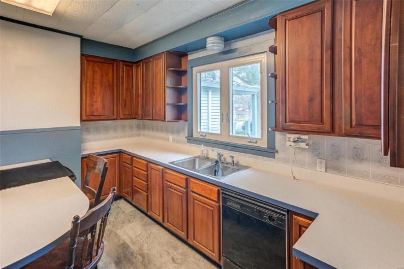 Kitchen with light countertops, a sink, open shelves, and black dishwasher