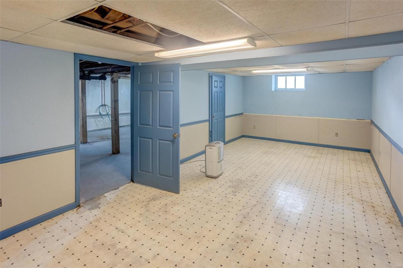 Basement featuring baseboards, light floors, and a drop ceiling