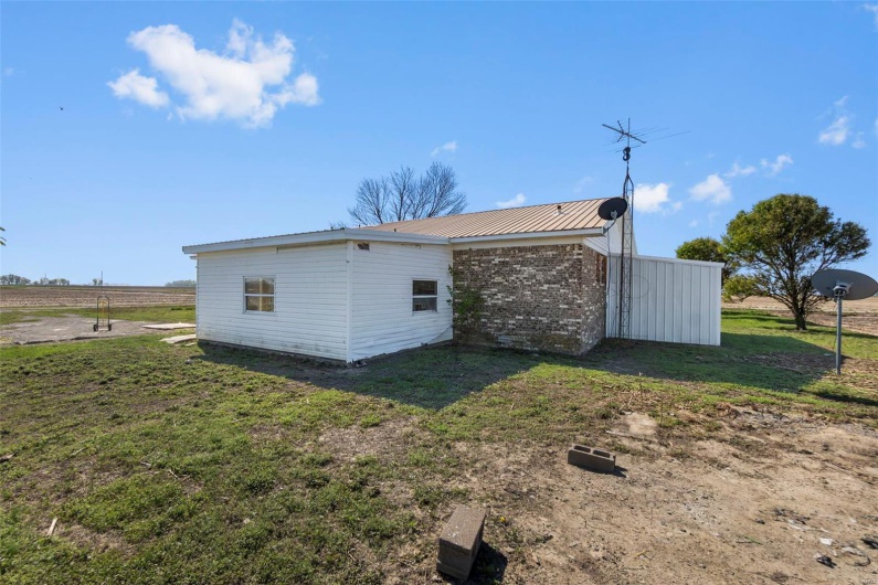 Back of property with brick siding, a lawn, and metal roof