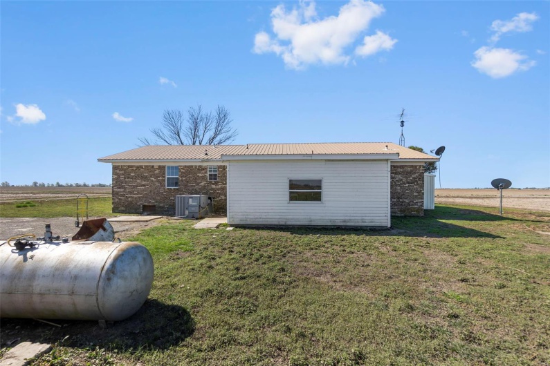 Rear view of house featuring central AC unit, a yard, and metal roof