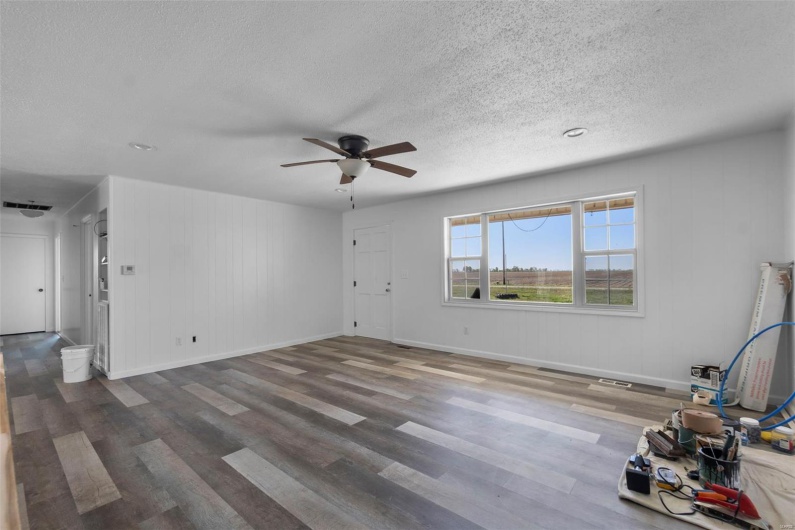 Unfurnished living room with wood finished floors, a textured ceiling, ceiling fan, and visible vents