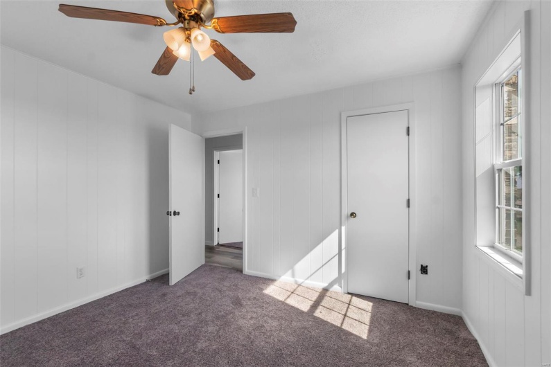 Unfurnished bedroom featuring carpet floors, a ceiling fan, and multiple windows