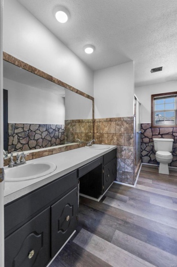 Bathroom featuring wainscoting, toilet, a sink, and tile walls