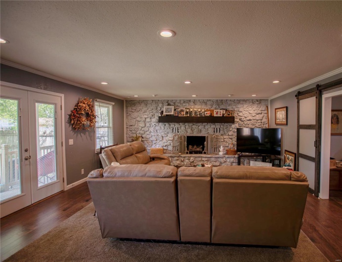 Living area with french doors, dark wood-type flooring, ornamental molding, and a barn door
