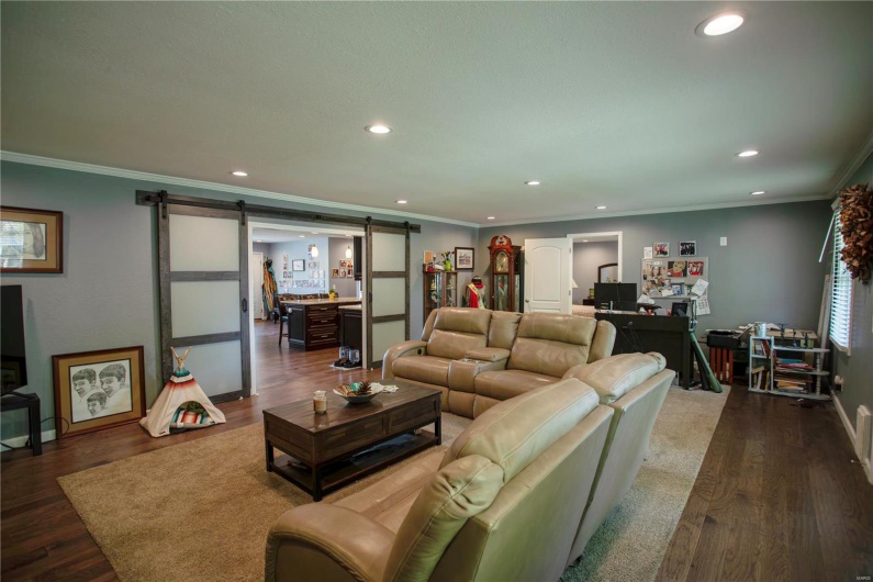 Living area featuring a barn door, ornamental molding, wood finished floors, and recessed lighting