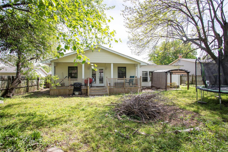 Back of house with fence, a lawn, a porch, and a trampoline
