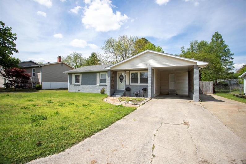 Ranch-style home featuring concrete driveway, a front lawn, a carport, fence, and brick siding
