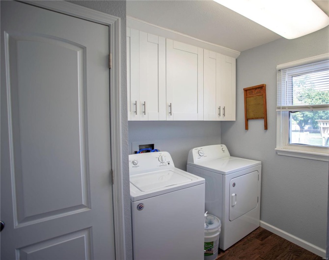 Laundry area with separate washer and dryer, dark wood-style flooring, cabinet space, and baseboards