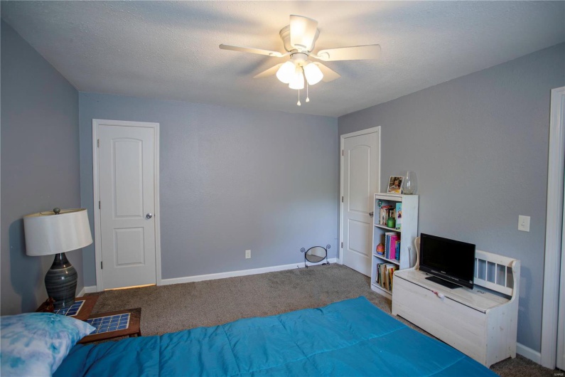 Carpeted bedroom with a ceiling fan and baseboards