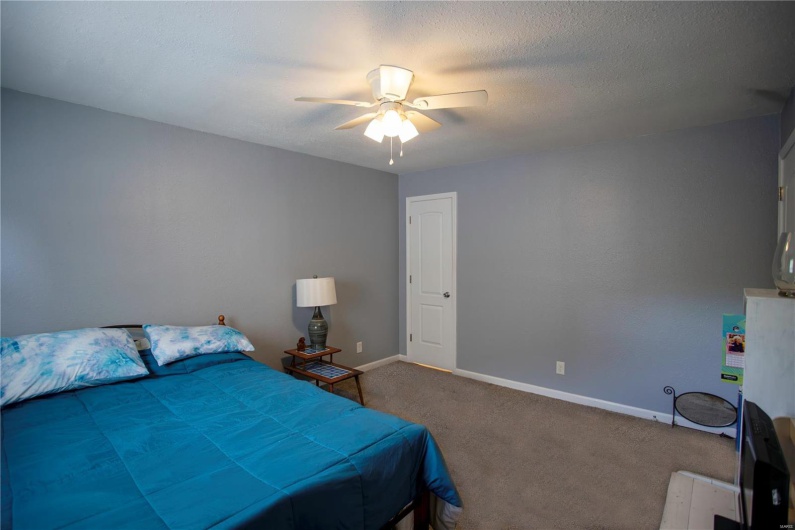 Carpeted bedroom with a ceiling fan and baseboards