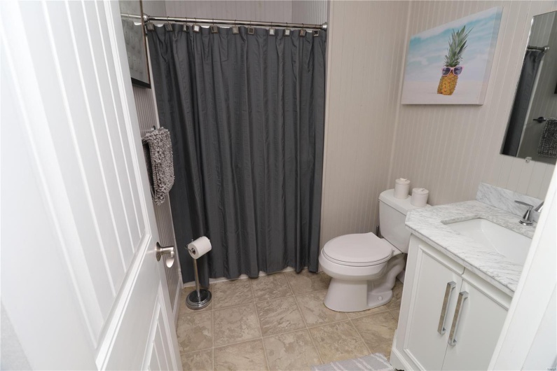 Bathroom featuring a shower with shower curtain, tile patterned flooring, toilet, and vanity