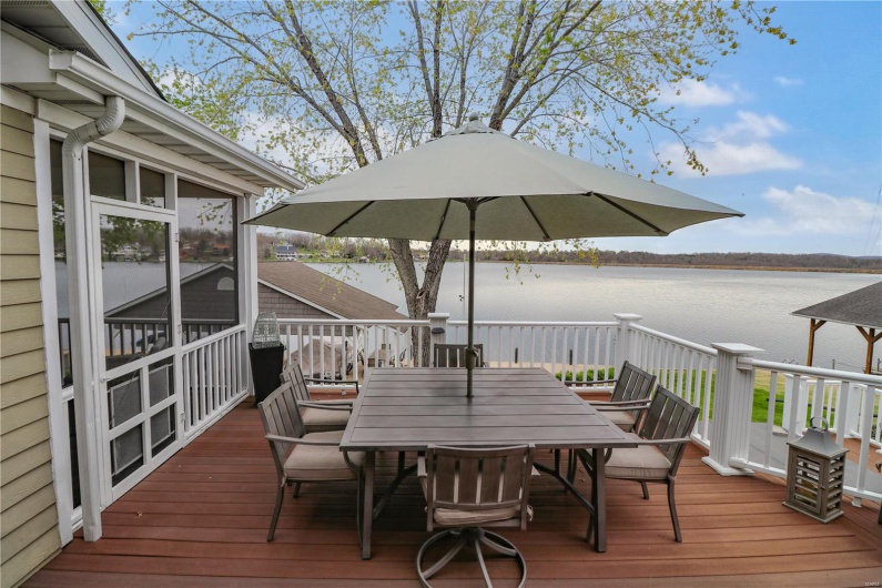 Wooden terrace featuring outdoor dining space, a sunroom, and a water view