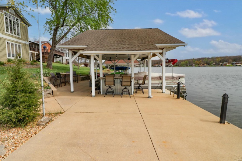View of dock featuring a gazebo, outdoor dry bar, a patio area, and a water view