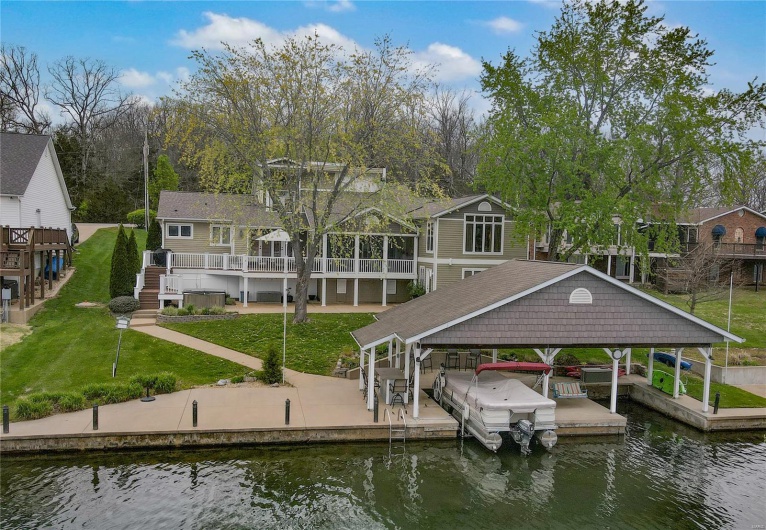 View of dock featuring a lawn, a water view, boat lift, a residential view, and stairs