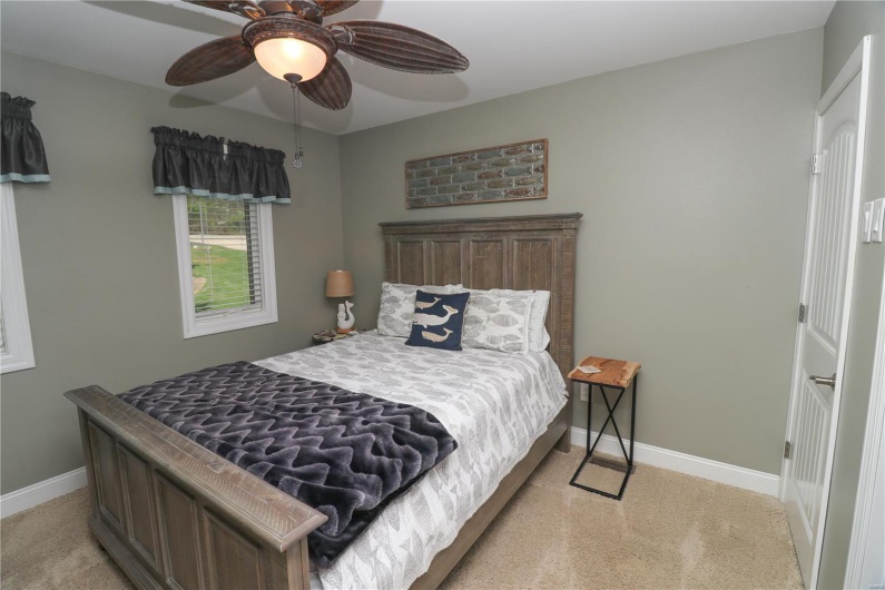 Bedroom featuring light colored carpet, baseboards, and a ceiling fan