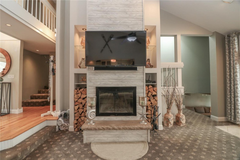 Living area with a glass covered fireplace, stairway, carpet flooring, and high vaulted ceiling