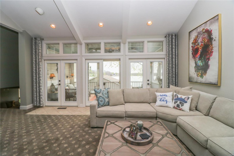 Carpeted living room featuring tile patterned floors, french doors, beamed ceiling, baseboards, and recessed lighting