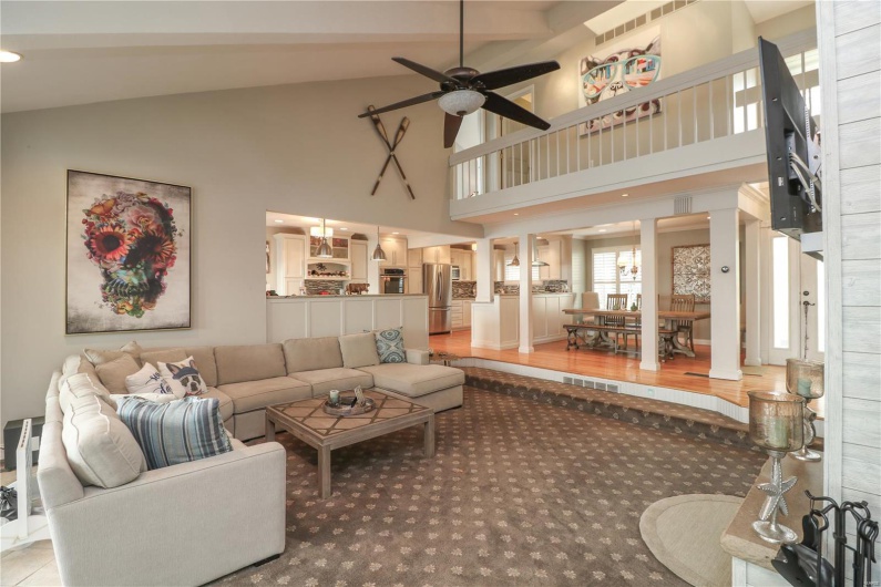 Living room with high vaulted ceiling, light carpet, a ceiling fan, and visible vents