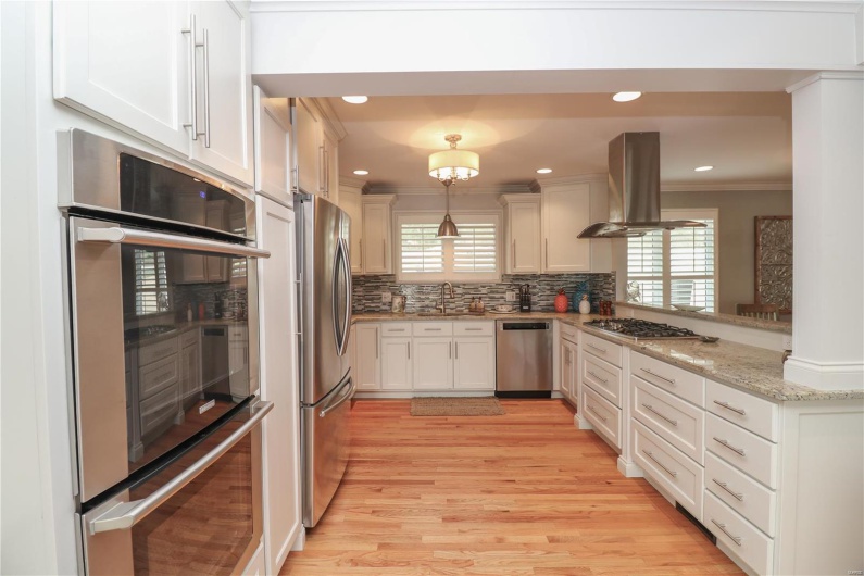 Kitchen featuring backsplash, island range hood, ornamental molding, a sink, and appliances with stainless steel finishes