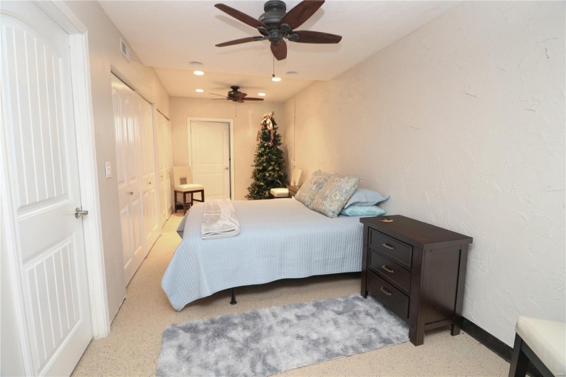 Bedroom featuring ceiling fan, a textured wall, baseboards, visible vents, and recessed lighting