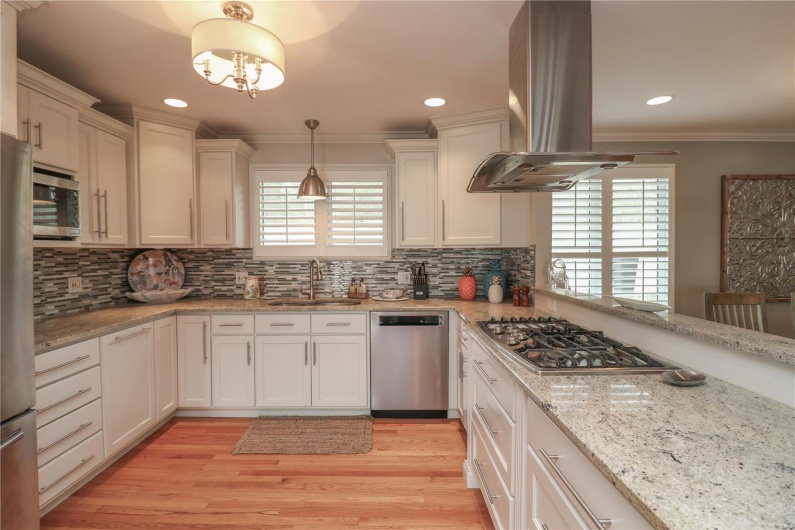Kitchen featuring island range hood, ornamental molding, a sink, tasteful backsplash, and appliances with stainless steel finishes