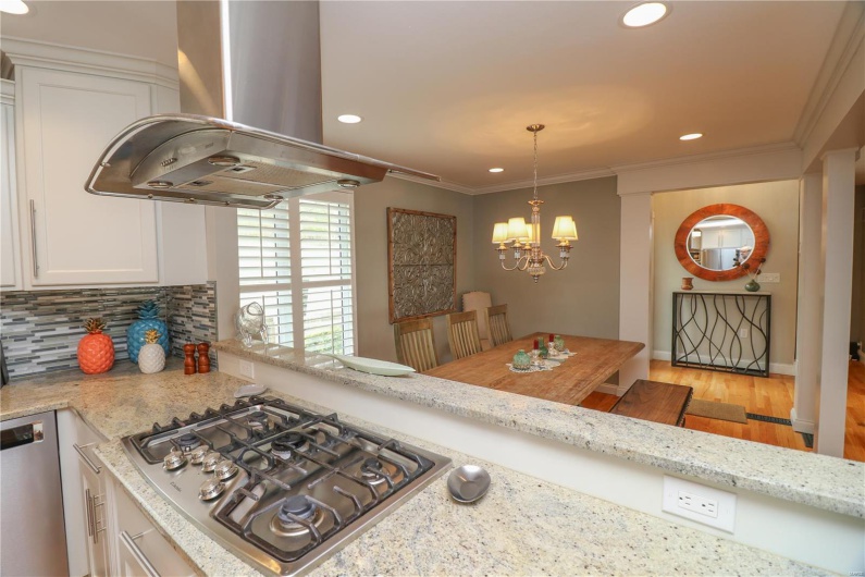 Kitchen featuring stainless steel appliances, island exhaust hood, an inviting chandelier, backsplash, and white cabinetry