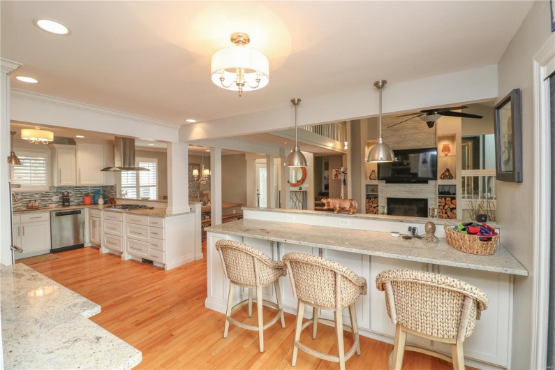 Kitchen with stainless steel appliances, a peninsula, island exhaust hood, light wood-type flooring, and open floor plan