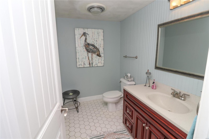 Half bath featuring baseboards, vanity, tile patterned flooring, and toilet