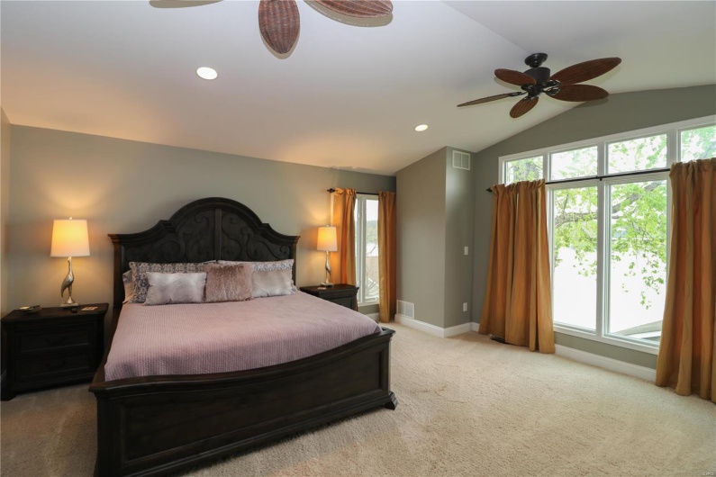 Bedroom featuring baseboards, lofted ceiling, visible vents, and light colored carpet