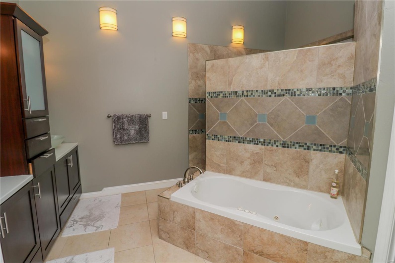 Bathroom featuring tile patterned flooring, a tile shower, vanity, and a relaxing tiled tub